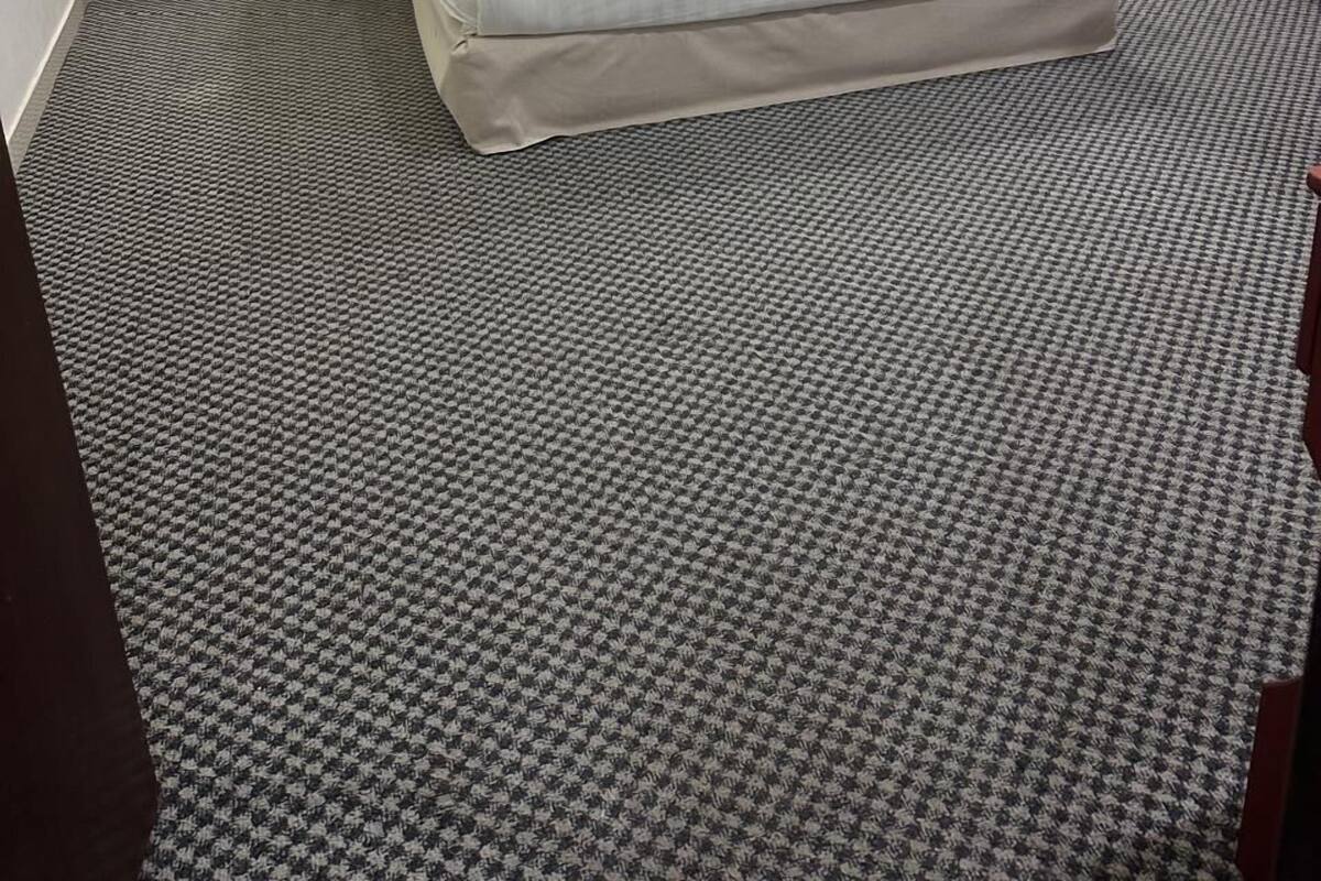 Ein Hotelzimmer mit einem Bett, zwei Nachttischen und einem Kopfteil.