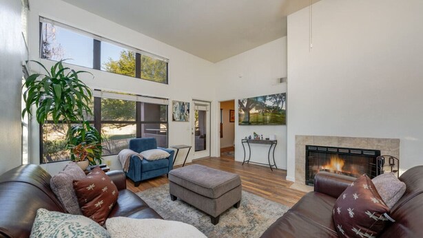 A spacious living room with a fireplace, leather sofas, a blue armchair, and a large plant. - East / Sabino / 2 BR 2BA / Golf View / Htd Pools (Tucson)