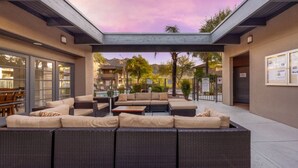 An outdoor seating area with a pergola, wicker furniture, and a pool in the background. - East / Sabino / 2 BR 2BA / Golf View / Htd Pools (Tucson)