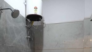 Ein kleines Badezimmer mit Fliesen, einer Toilette, einer Dusche und einem Händetrockner.