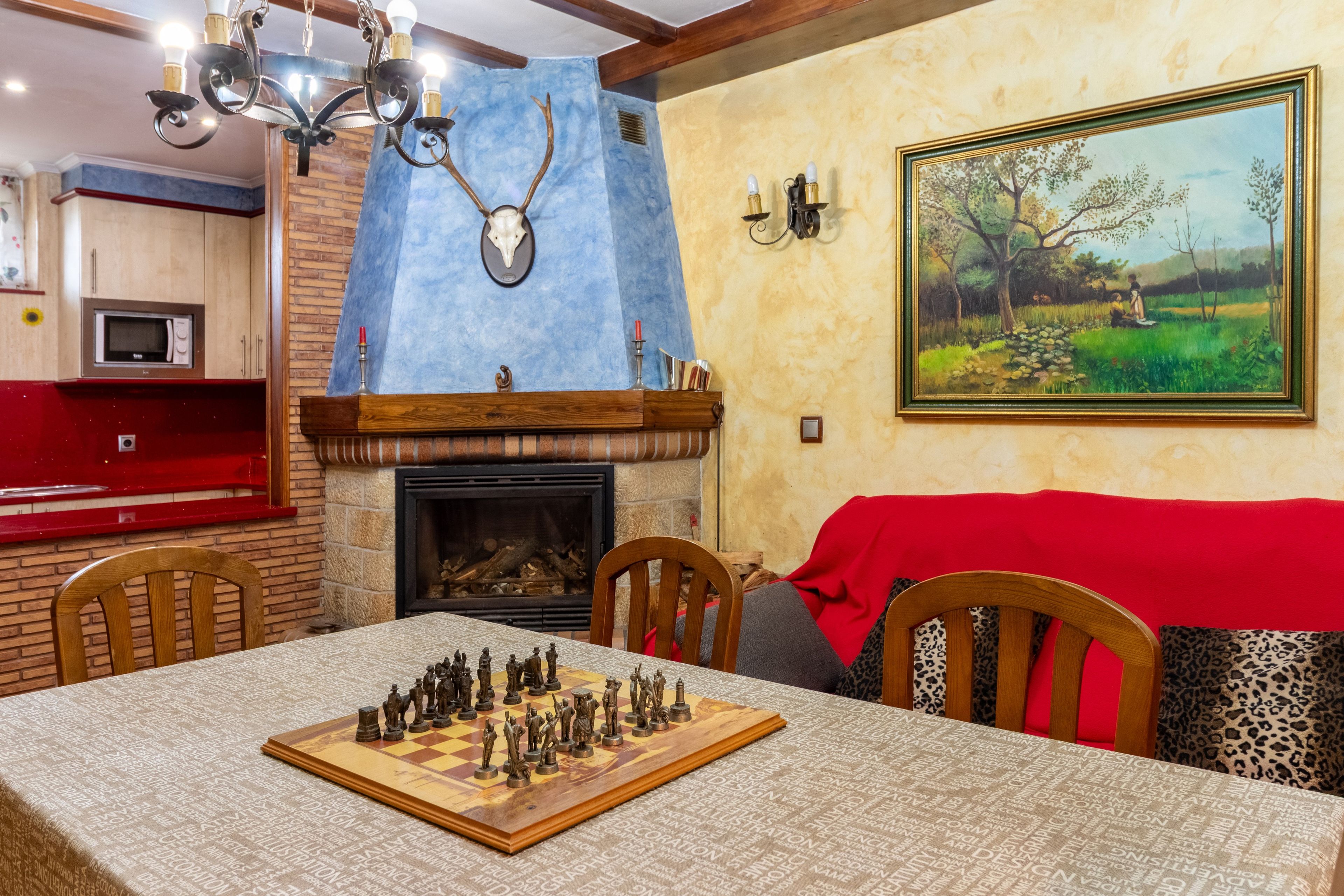 A dining area with a chessboard, a fireplace, and a painting on the wall.