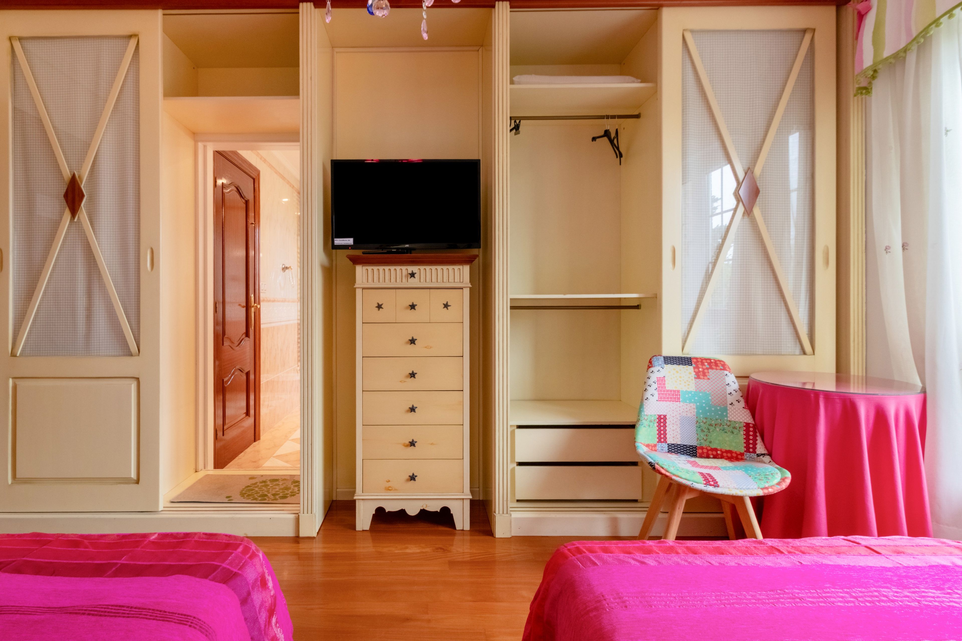 Ein Schlafzimmer mit einem Bett, einem Schminktisch, einem Fernseher und einem Sessel.