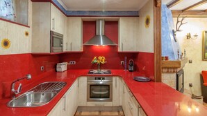 Una cocina con encimera roja, pileta de acero inoxidable, horno y microondas.