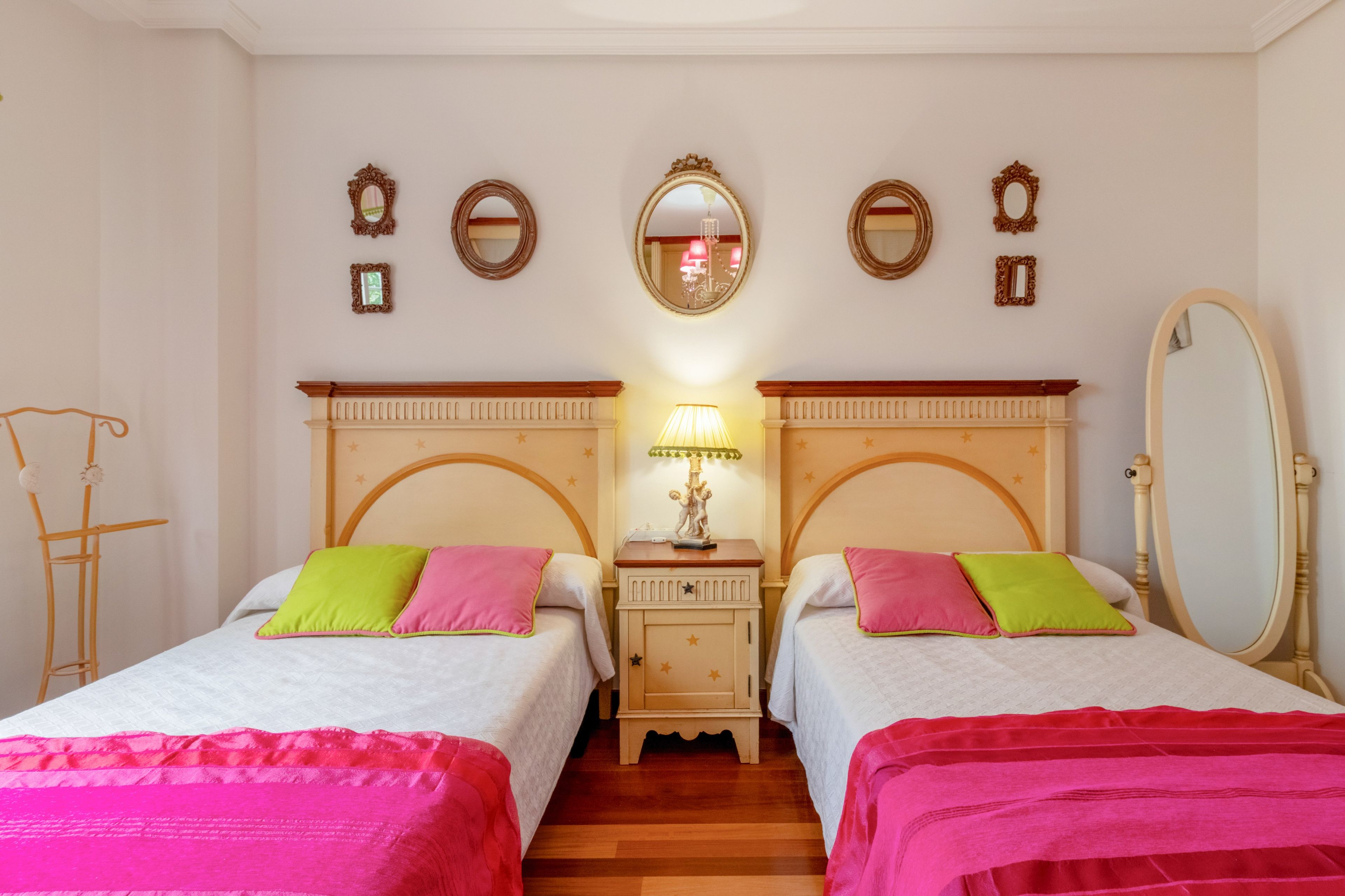 A double room with two beds, a nightstand with a lamp, and a mirror on the wall.