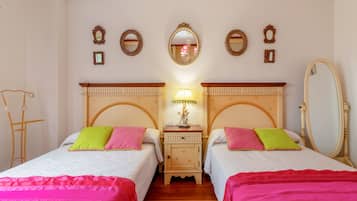 A double room with two beds, a nightstand with a lamp, and a mirror on the wall.