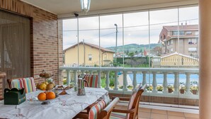 Un balcón con una mesa dispuesta para el desayuno, vista al mar y un muro de ladrillo.