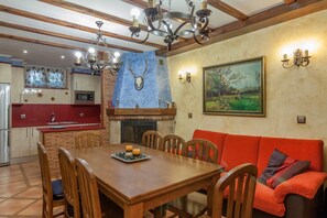 A dining area with a wooden table and chairs, a fireplace, and a painting on the wall.