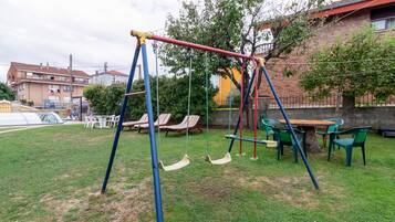 Une aire de jeux avec des balançoires et une table entourée de chaises.