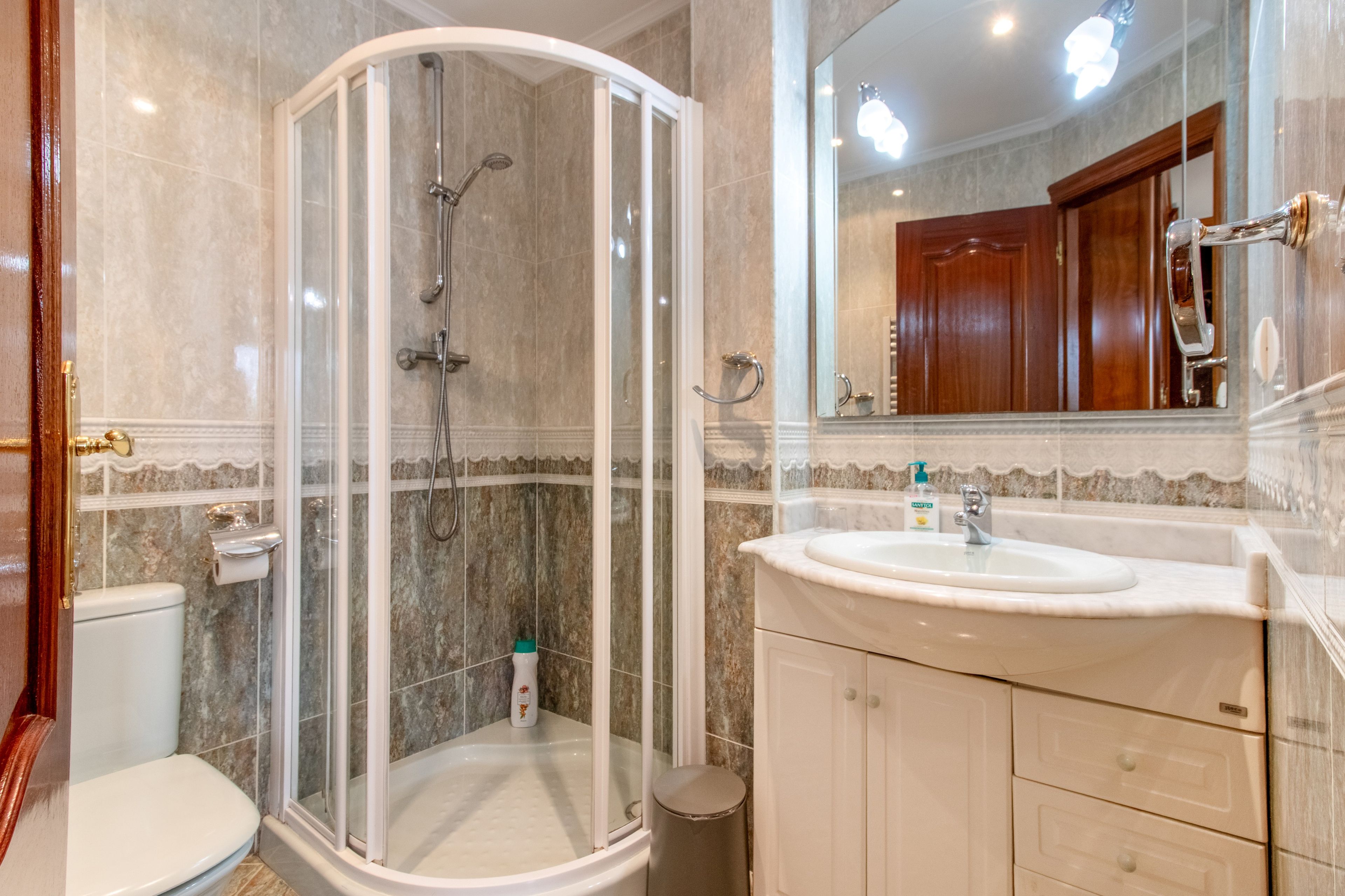 Une salle de bain avec une douche à parois de verre, un lavabo et des toilettes.