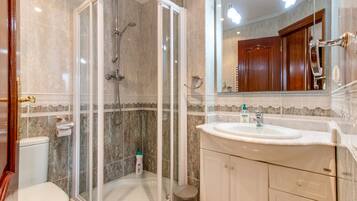 Une salle de bain avec une douche à parois de verre, un lavabo et des toilettes.