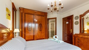 A bedroom with a large bed, wooden wardrobe, a shower, and a chandelier. - 'Alojamientos Marte Room 2' with Shared Terrace and Garden (Torrelavega)