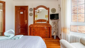 A bedroom with a bed, dresser, mirror, television, and a window with curtains. - 'Alojamientos Marte Room 2' with Shared Terrace and Garden (Torrelavega)