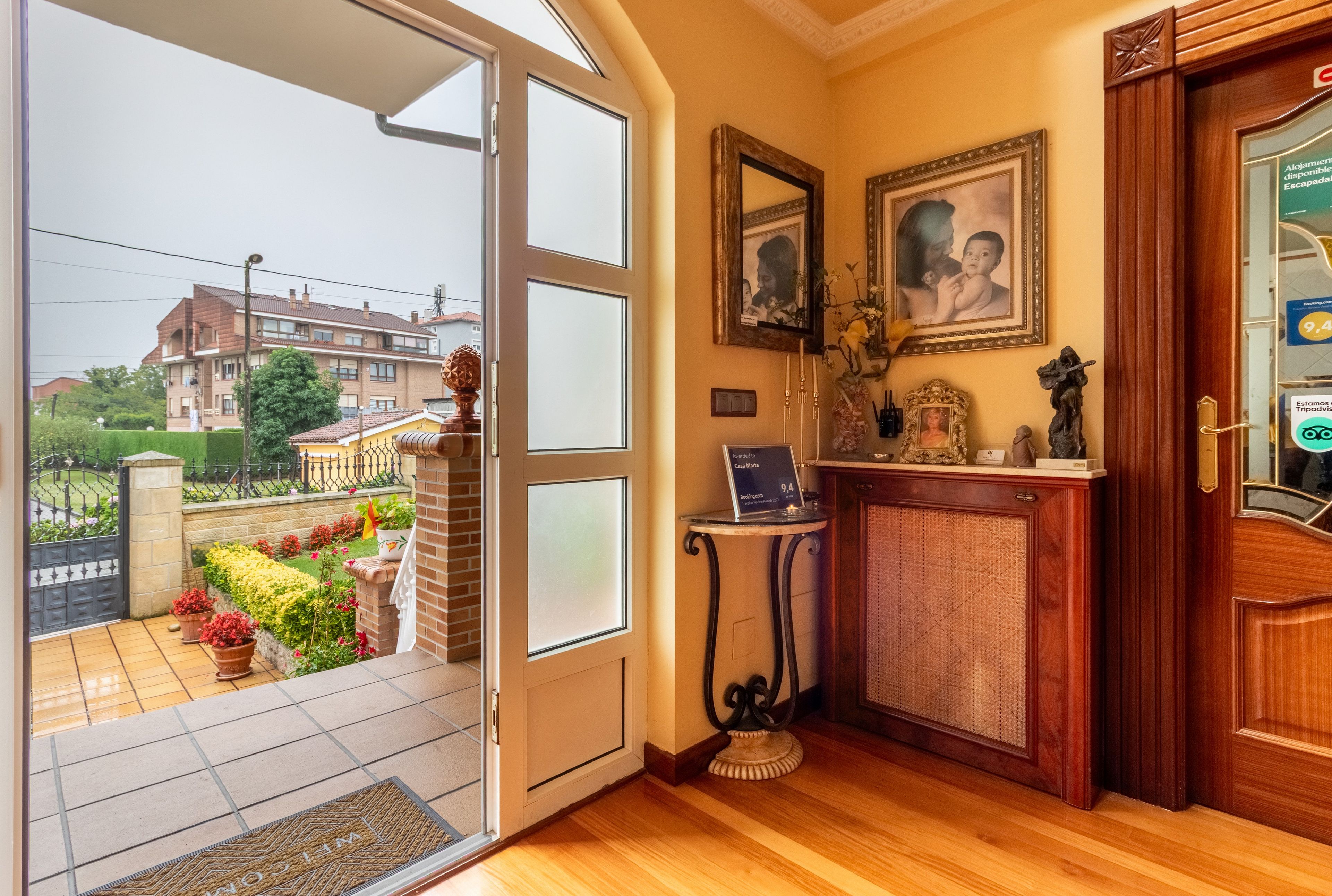 A room with a wooden door, a small table with a laptop, and two framed pictures on the wall.