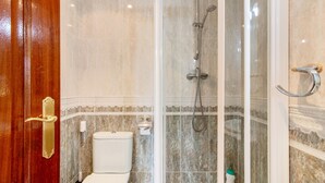 A bathroom with a toilet, a shower enclosure, and a marble-tiled wall. - 'Alojamientos Marte Room 2' with Shared Terrace and Garden (Torrelavega)