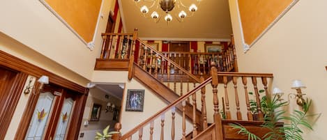 A grand staircase with wooden balusters and a chandelier.