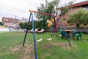Un parc infantil amb cadira d'oscil·lació i taula amb cadires.