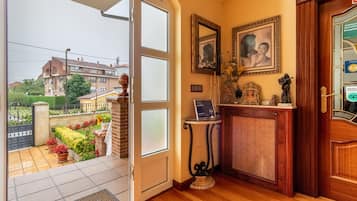 Une pièce avec une porte en bois, une petite table sur laquelle se trouve un ordinateur portable, et deux tableaux encadrés accrochés au mur.