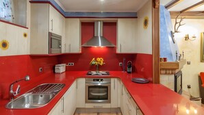 Una cocina con encimera roja, electrodomésticos de acero inoxidable y una isla central con un jarrón de flores.