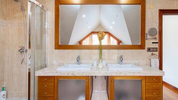 Une salle de bain avec une douche, deux lavabos, un grand miroir et des meubles en bois.