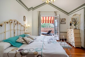 Ein Schlafzimmer mit einem Bett, einer Kommode, einem Sessel und Blick ins Freie.