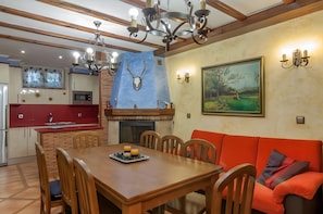 Un comedor con una mesa de madera, sillas, un sofá rojo y una chimenea.