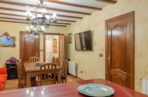 Un coin repas avec une table en bois, des chaises, un lustre et une nappe rouge.