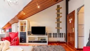 A modern living room with a flat-screen TV, a bookshelf, a red sofa, and a decorative wall with wooden signs.