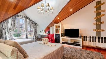 Ein Schlafzimmer mit schrägen Wänden, einer Chandelierleuchtreibe, einem Bett mit Handtuch, einem Fernseher, einem Klavier und einer Wand mit Hinweisschildern.