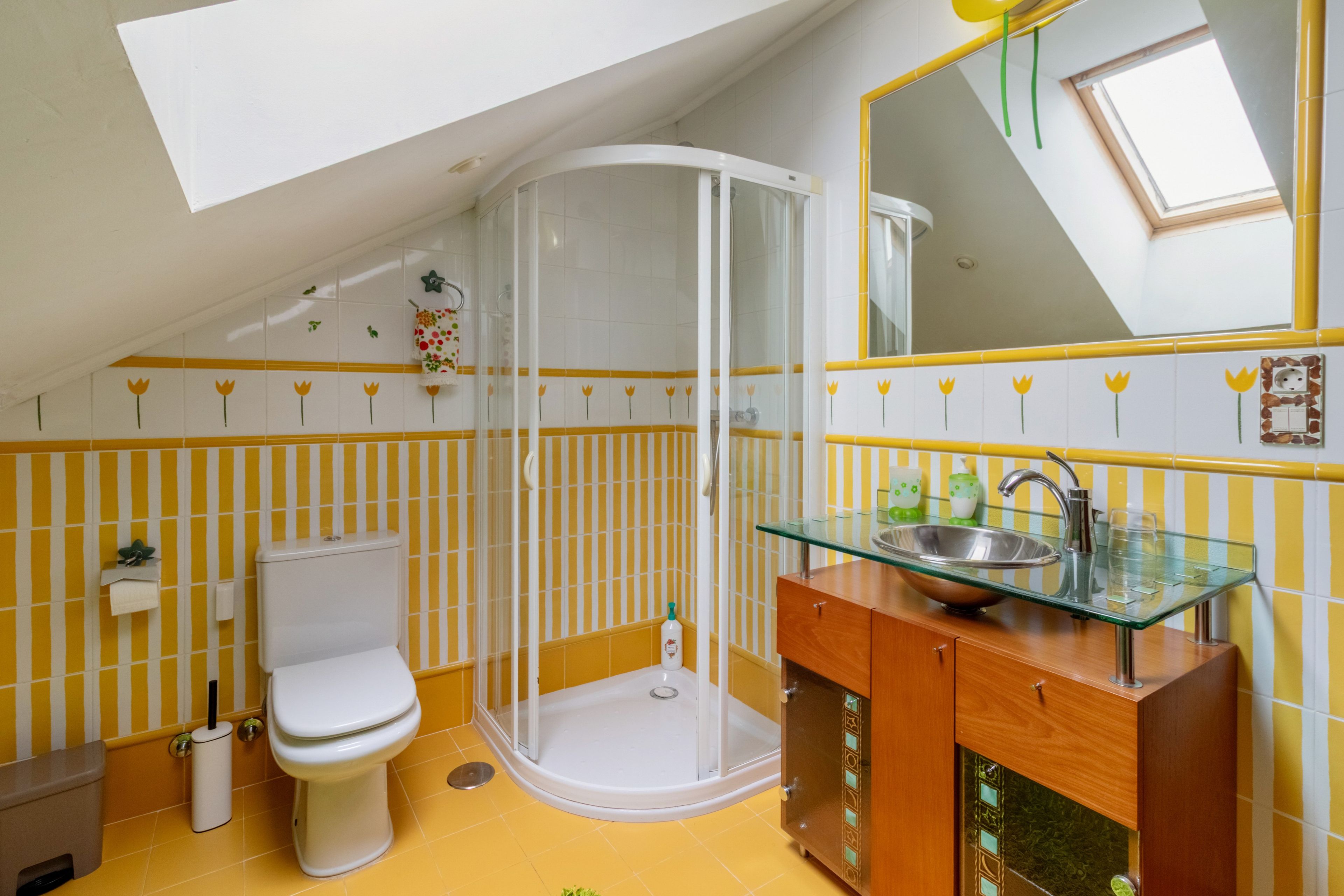Un baño con cabina de ducha de vidrio, inodoro y lavamanos con encimera de cristal.