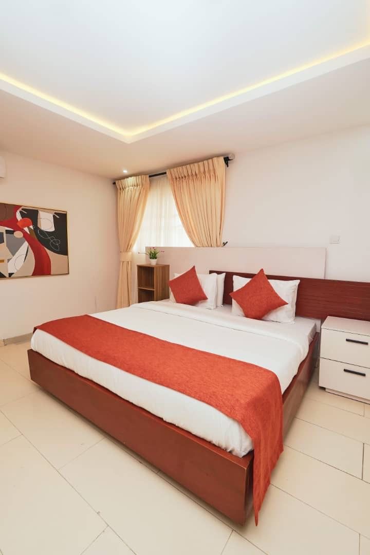 A modern hotel room with a large bed, a bedside table, and a nightstand.