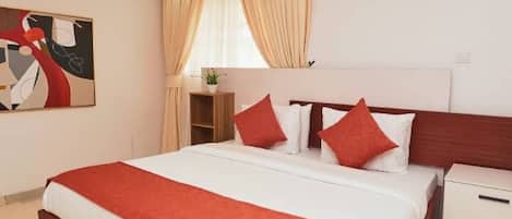 A modern hotel room with a large bed, a bedside table, and a nightstand.