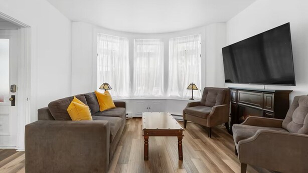 A modern living room with a sofa, armchairs, a coffee table, and a flat-screen TV. - Perfect Location! Perfect Stay in Quebec City!
Suite Jardin (Québec)