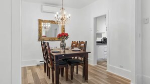 A dining area with a wooden table, chairs, a chandelier, a mirror, and a vase with flowers. - Perfect Location! Perfect Stay in Quebec City!
Suite Jardin (Québec)