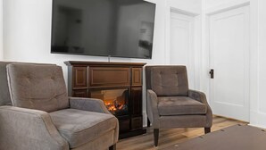 A living room with a flat-screen TV mounted above a fireplace, two armchairs, and a coffee table. - Perfect Location! Perfect Stay in Quebec City!
Suite Jardin (Québec)