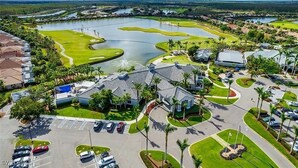 Luftaufnahme eines Golfplatzes mit einem großen Teich, umgeben von Wohngebäuden und einem Parkplatz.