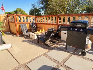 An outdoor patio area with a fire pit, seating, and a barbecue grill.