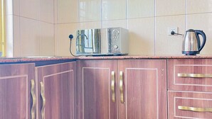 Une cuisine avec des meubles de rangement en bois, un four à micro-ondes et une bouilloire.