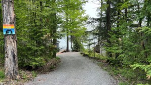 A gravel path leading to a cabin in a forested area with a sign indicating Sandy Lake. - Beautiful Sandy Lake Cabin (as seen on HGTV) (Trent Lakes)