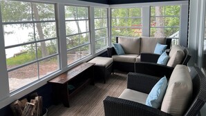 A sunroom with large windows, a cushioned seating area, and a wooden bench. - Beautiful Sandy Lake Cabin (as seen on HGTV) (Trent Lakes)