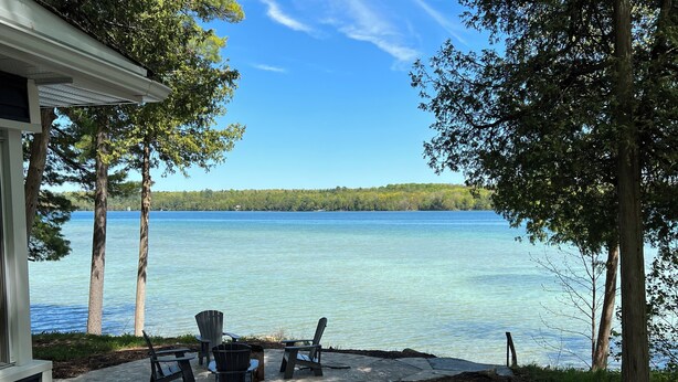 A lakeside patio with Adirondack chairs and a stone pathway leading to the water. - Beautiful Sandy Lake Cabin (as seen on HGTV) (Trent Lakes)