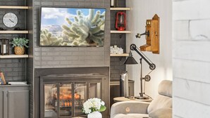A modern living room with a fireplace, a television mounted on the wall, and a cozy seating area. - Charming Pines Cabin / Fireplace + BBQ Retreat (Show Low)