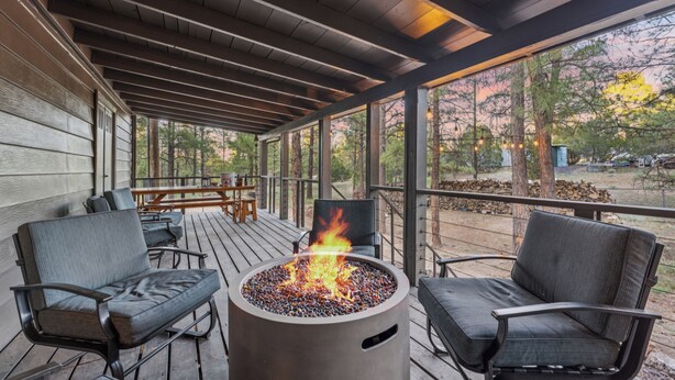 A covered outdoor area with a fire pit, seating, and a view of the surrounding trees. - Charming Pines Cabin / Fireplace + BBQ Retreat (Show Low)