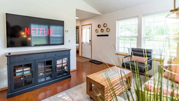 A modern living room with a flat-screen TV, a wooden coffee table, and a black leather sofa. - Quiet/New 2bd Suite w/ Laundry, Kitchen, Wi-Fi (Palmer)