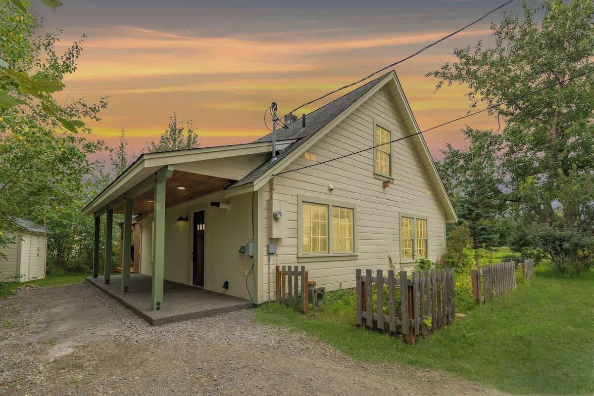 Une maison de plain-pied avec un porche couvert, une porte d’entrée et un petit jardin clos.