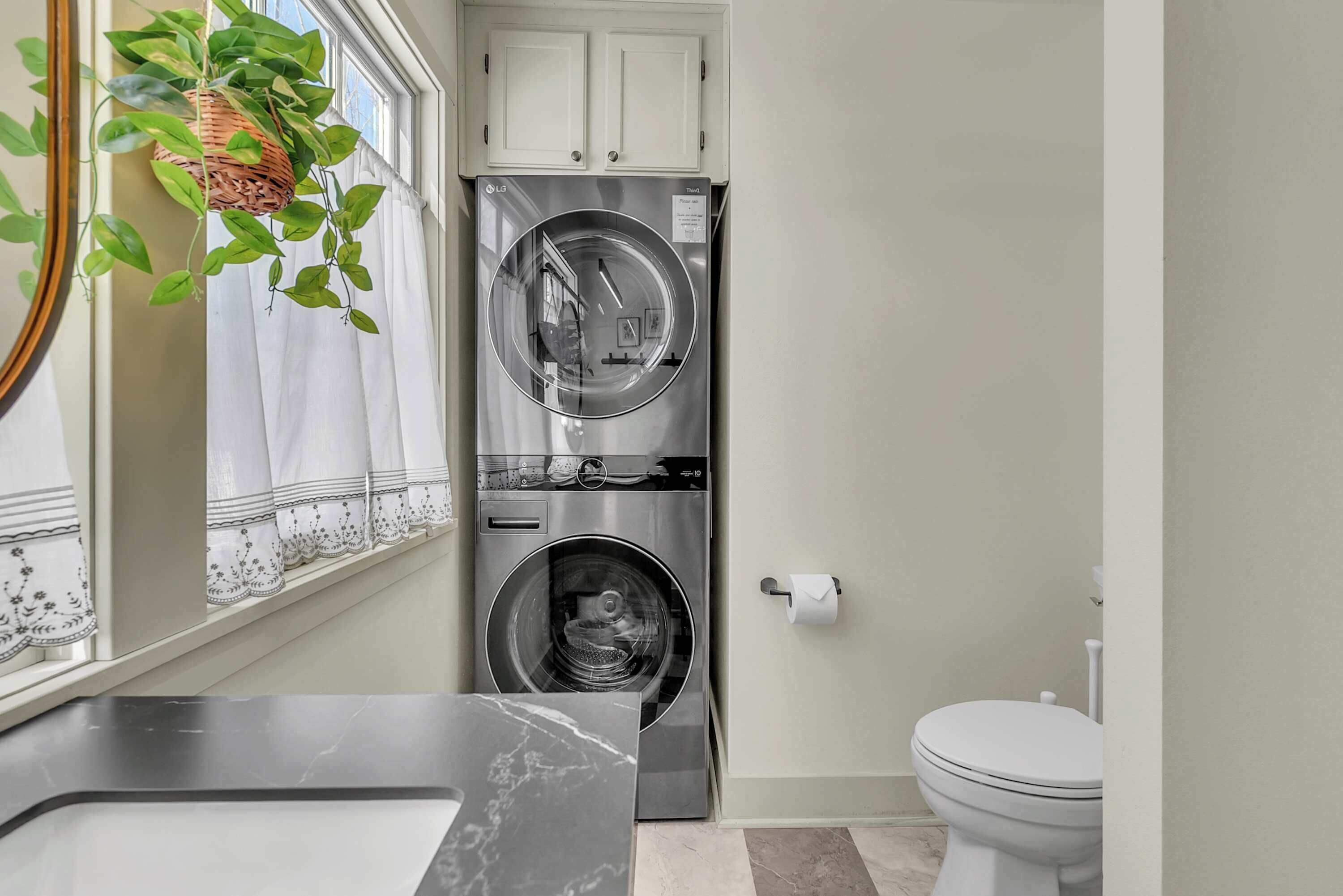 A compact laundry room with a washing machine, a dryer, and a toilet.