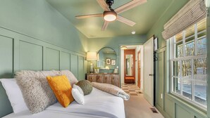 A bedroom with a bed, a ceiling fan, a window with a view, and a hallway leading to a bathroom. - Hot Tub w/ Mt Views, Full Kitchen, Laundry (Palmer)