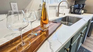 A kitchen with a marble countertop, a wine bottle, and two wine glasses.