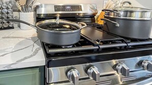 A modern kitchen with a stainless steel stove, two pots, and a digital control panel.