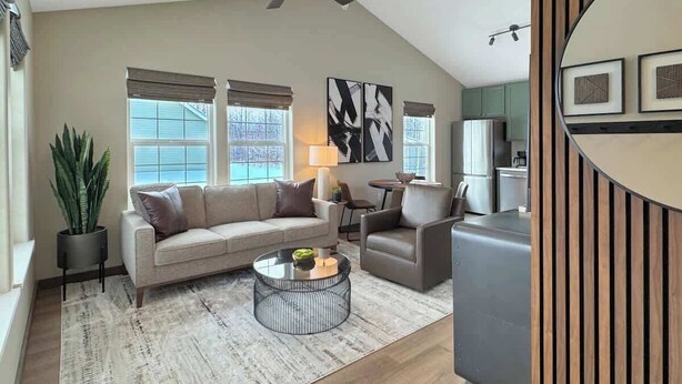 A modern living room with a sofa, armchairs, a coffee table, and a dining area.