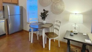 A compact kitchen with a refrigerator, dining table with chairs, and a small side table with a lamp and a plant. - Private & Quiet! 2bd/2ba w/ Laundry & Mt. Views! (Palmer)